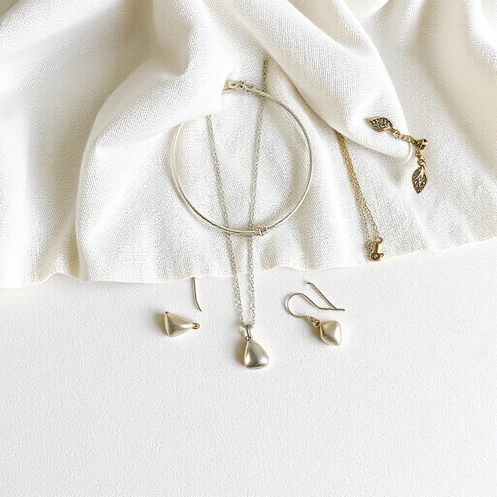 Assorted handmade sterling silver necklace, bracelet, and earrings on a light fabric background