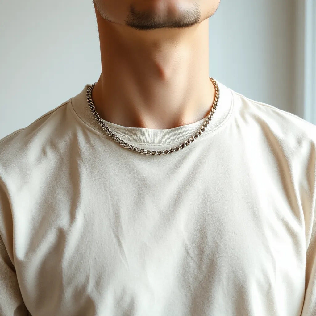 Man wearing a simple silver chain necklace over a plain crew-neck shirt