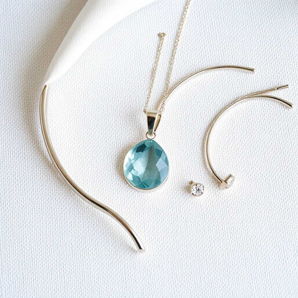 Silver pendant, bracelet, and earrings displayed on neutral fabric with crisp, polished details