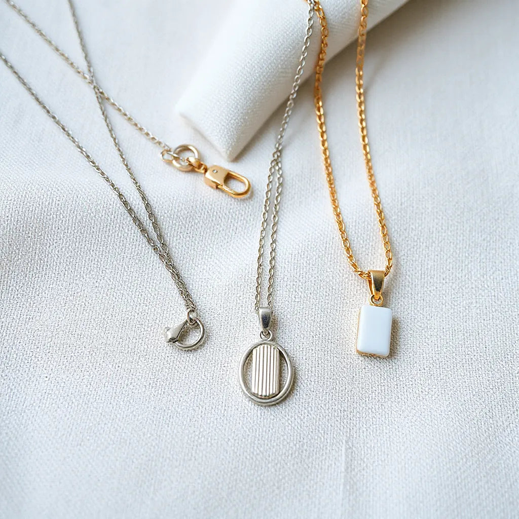 Multiple silver necklaces with visible chain links and clasps on neutral fabric background