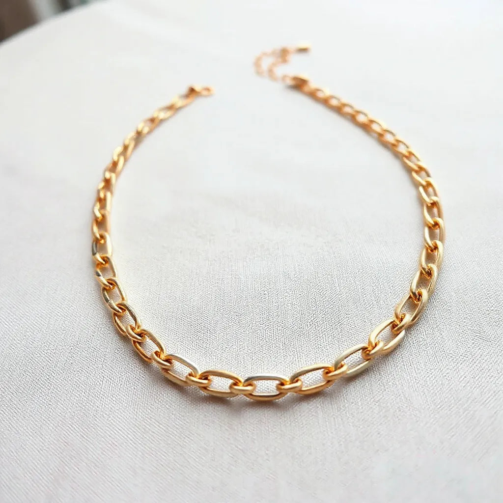 Multi-tone chain necklace with alternating metal tones on a neutral fabric background