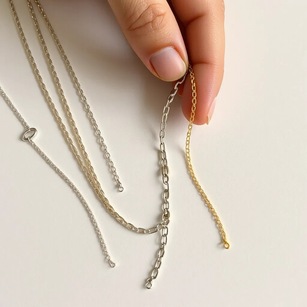 Flexible linked chains in silver and gold tones, styled on a neutral surface with a hand adjusting the drape