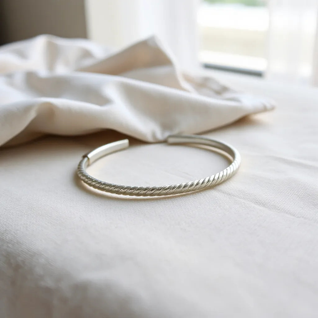 Polished 925 sterling silver bracelet on neutral fabric with soft light and subtle polishing cloth