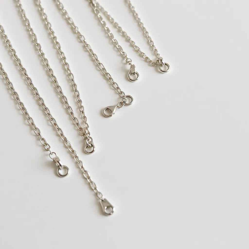 Assorted 925 sterling silver chains with distinct link patterns arranged on a neutral background