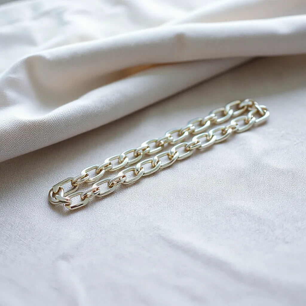 Mens silver chain resting on neutral fabric with soft highlights on the links