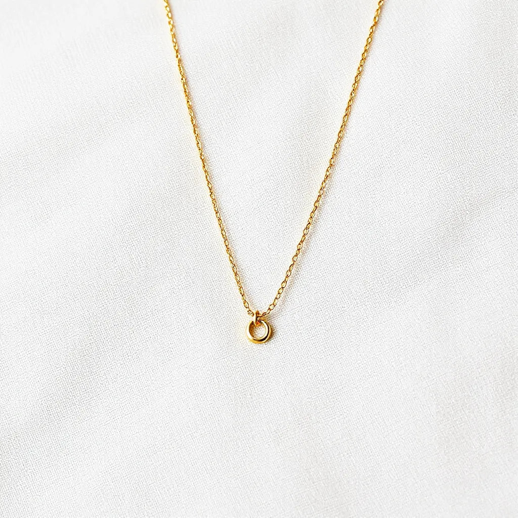 14k gold vermeil necklace with delicate chain and small minimalist pendant on neutral fabric