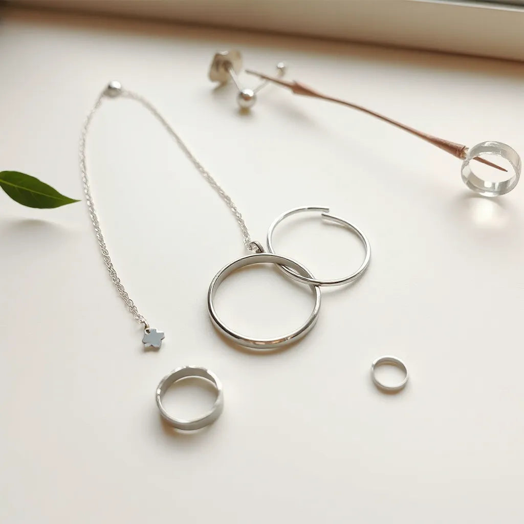 Necklace, bracelet, earrings, and a ring in polished silver arranged neatly on a light background.