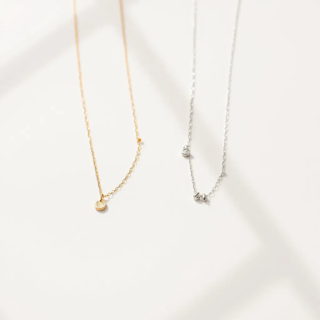 Minimal still-life of layered gold and silver chain necklaces with small round pendants
