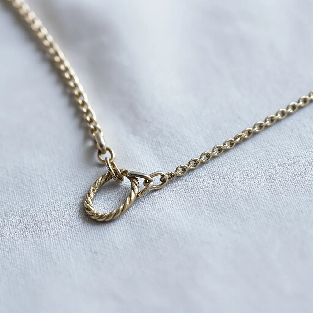 Timeless silver rope chain with detailed links laid on light gray fabric under soft studio lighting