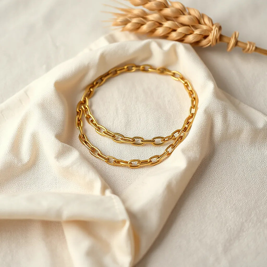 Wheat chain necklace laid neatly on light neutral fabric with soft, warm lighting and visible link detail