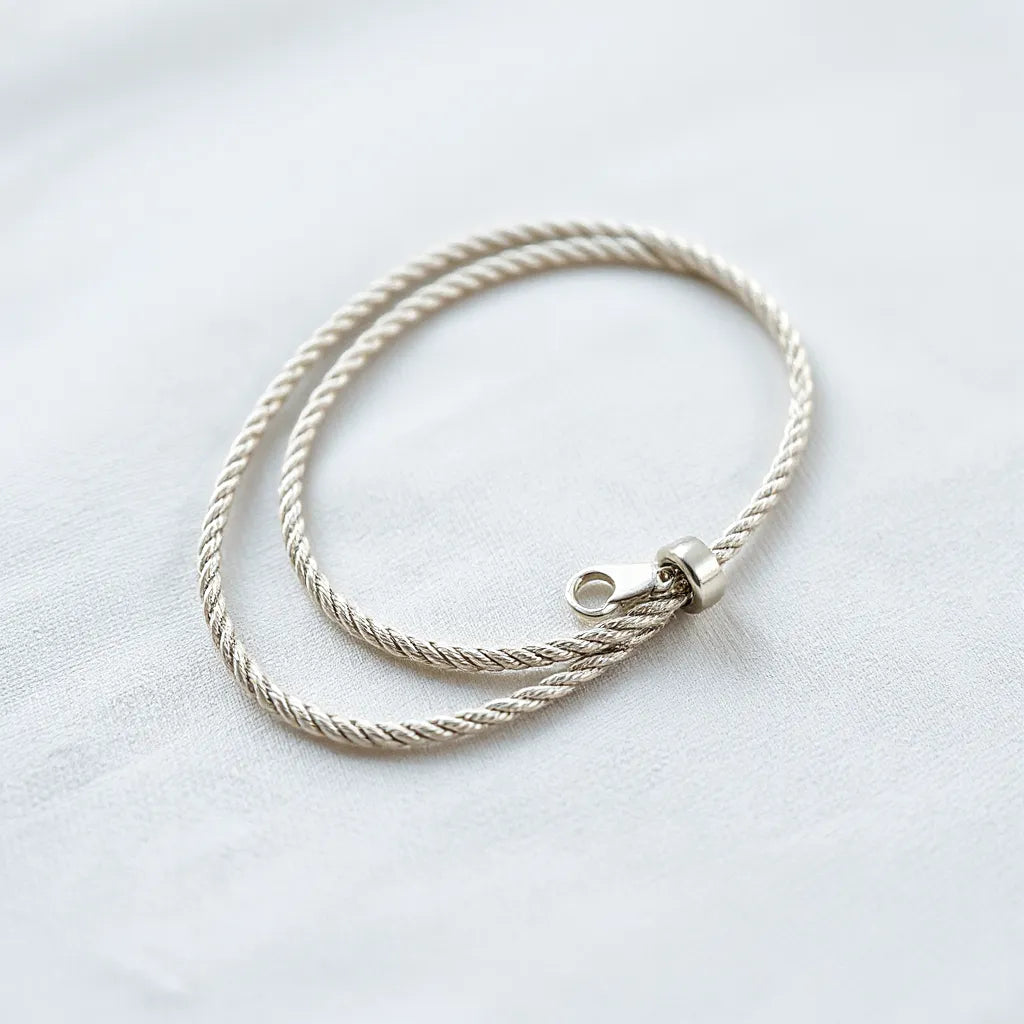 Silver rope chain necklace with visible textured links on a light neutral background