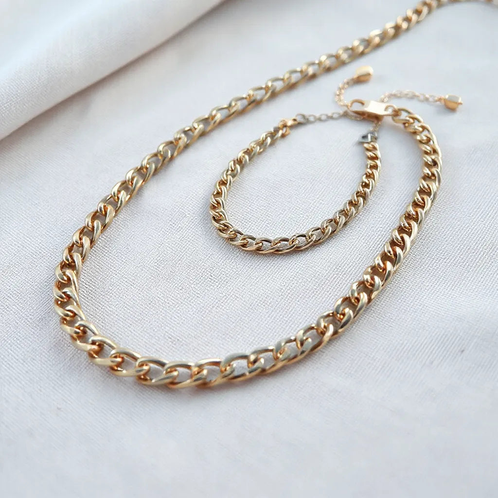 Polished franco chain necklace and bracelet with clear link detail on a neutral fabric background
