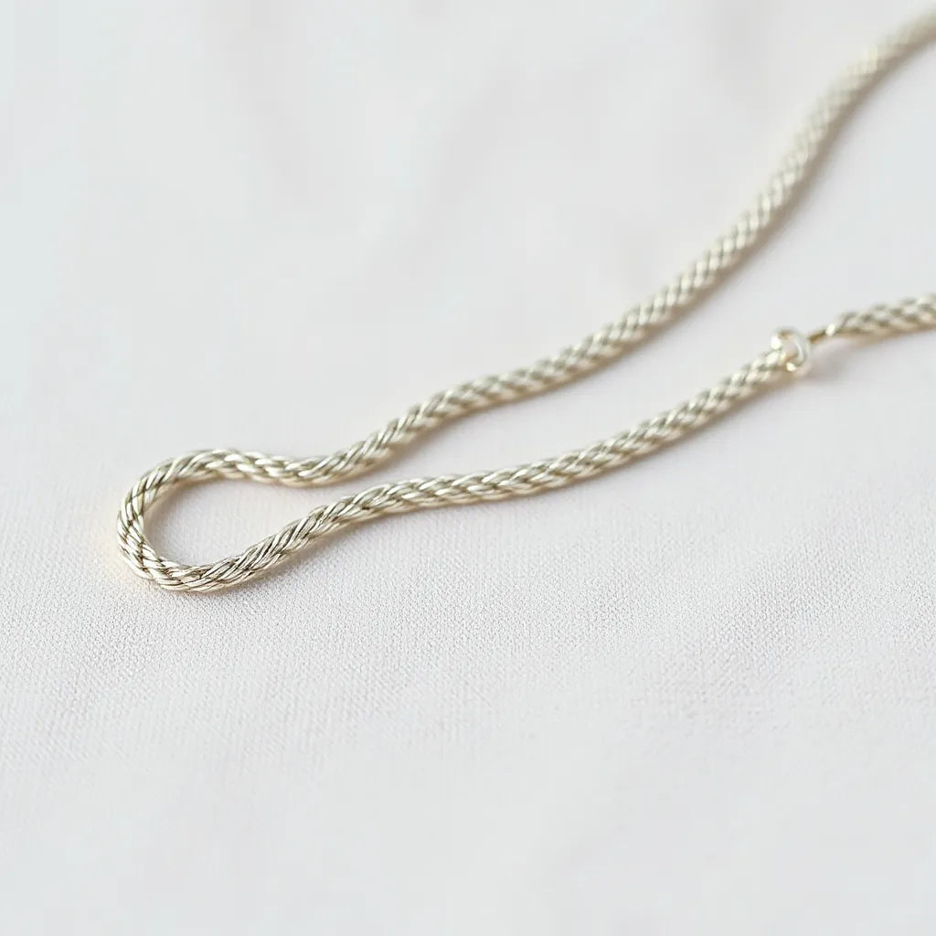 Classic silver rope chain with detailed twisted links on neutral fabric background
