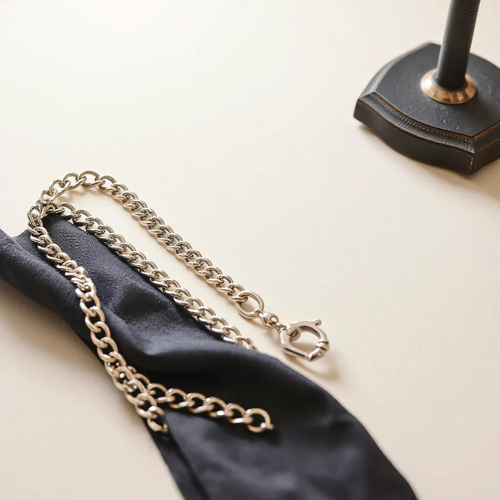 Polished silver chain with mirror-like shine draped neatly on a light neutral background