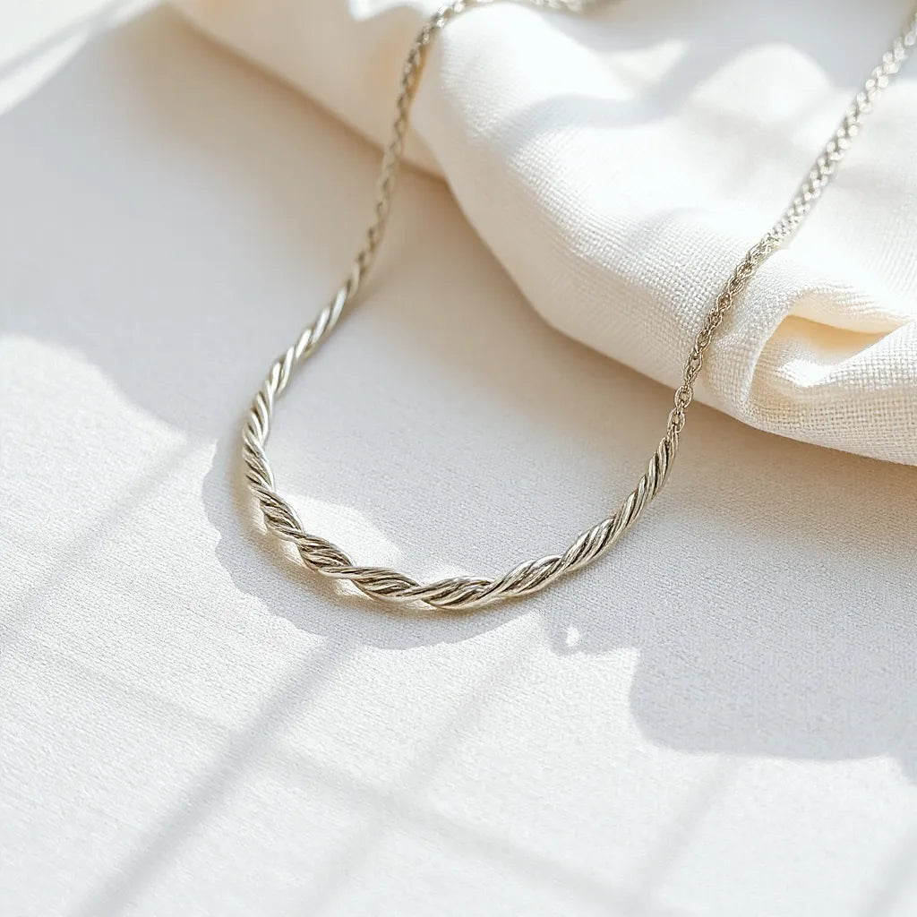 Silver rope chain necklace with soft reflections on a light fabric, paired with a polishing cloth