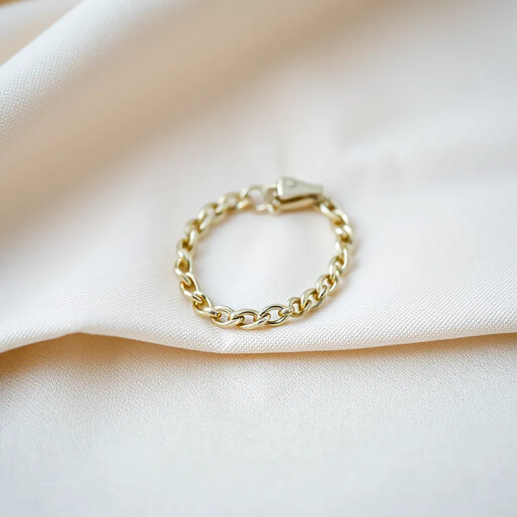 Polished figaro chain bracelet resting on soft neutral fabric with subtle shine and reflections