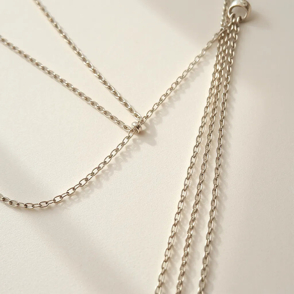 Handmade silver chains arranged neatly on a neutral background with visible link details